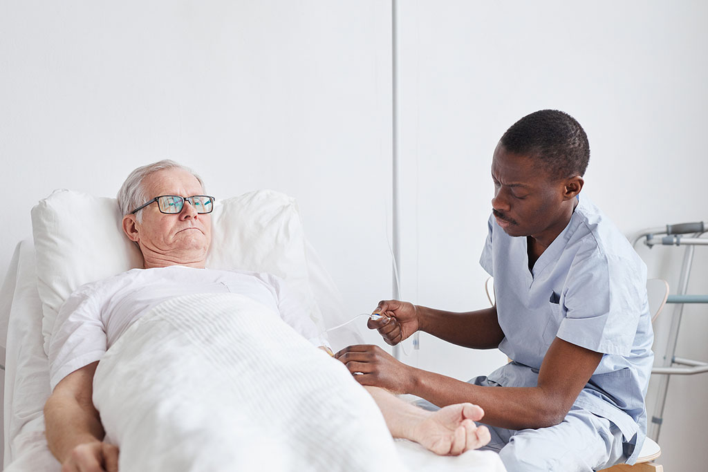 An African American Man Preparing IV Therapy for a Senior Man Laying on a Bed Benefits of Senior IV Therapy