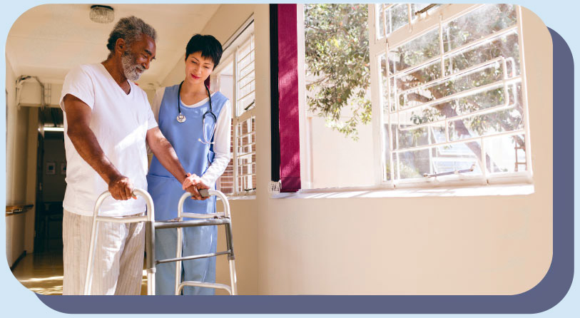 An elderly African American man using a walker with a skilled nurse standing beside him